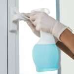 hands with gloves disinfecting window handle